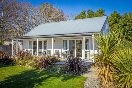 a white house with a conservatory in a garden at Greyfriars Motel in Greytown