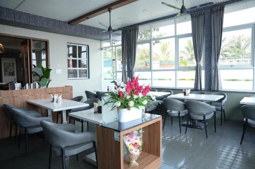 a dining room with tables and chairs and windows at Hotel Regency Grand in Shikrapur