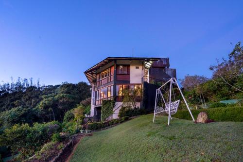 a house on top of a hill with a swing at Amansara Bungalow - Panoramic Lake View Villa, Nuwara Eliya in Nuwara Eliya