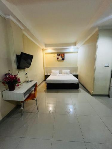 a hotel room with a bed and a television at Hotel Alden in Makassar