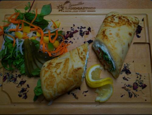 a sandwich and a salad on a cutting board at Hotel Zum Stern Spreewald in Werben