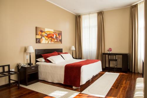 a bedroom with a large bed with red and white pillows at Hotel Victoria Plaza in Tarija