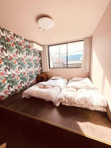 a bedroom with two beds and a floral wall at ゲストハウスシナノスイー Guest House Shinano Swee in Omachi