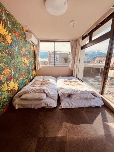 a bedroom with two beds and a painting on the wall at ゲストハウスシナノスイー Guest House Shinano Swee in Omachi