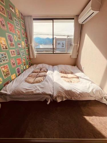 a bed in a room with a window at ゲストハウスシナノスイー Guest House Shinano Swee in Omachi
