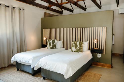 a bedroom with two beds with white sheets and pillows at Uitsig Boutique Hotel in Welkom