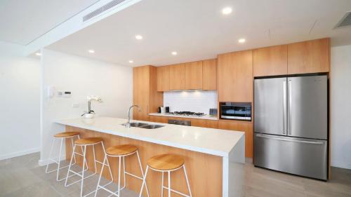 a kitchen with a stainless steel refrigerator and wooden cabinets at Oceans Edge #7 Accom Holidays in Terrigal