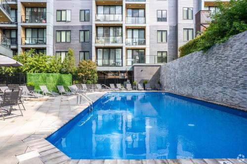 a swimming pool with chairs and a building at Chic 1BR Retreat - Pool, Gym Balcony Views in Philadelphia