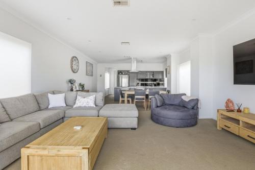 a living room with a couch and a table at 19th Hole Golf, Wine & Sea in Normanville