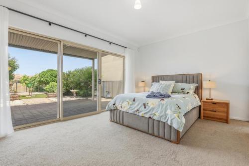 a bedroom with a bed and a sliding glass door at 19th Hole Golf, Wine & Sea in Normanville