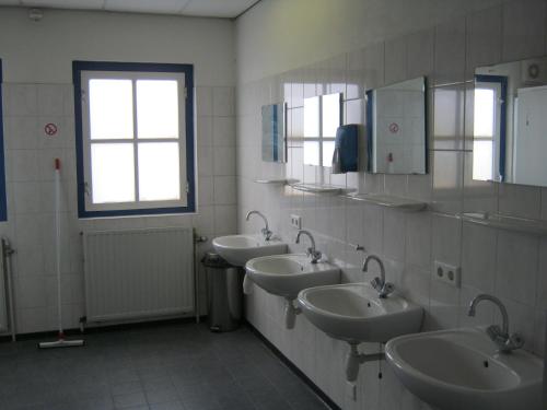 La salle de bains est pourvue de 3 lavabos et de 2 miroirs. dans l'établissement Pension Zevenbergen, à Zevenbergen
