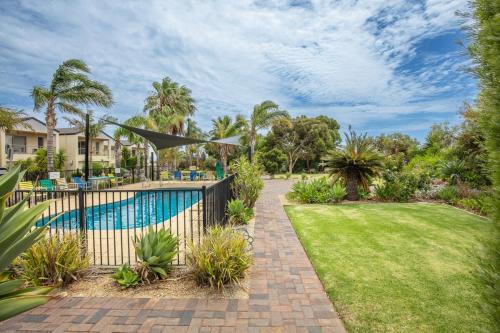 a garden with a fence and a swimming pool at 19th Hole Golf, Wine & Sea in Normanville