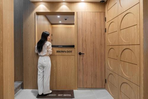 a woman standing in front of a wooden door at Brown Dot Hotel Incheon Bupyeong in Incheon