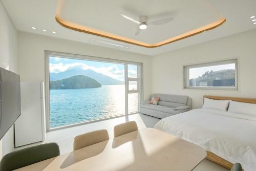 a bedroom with a large window overlooking the water at Geoje The Shine Pool Villa in Geoje