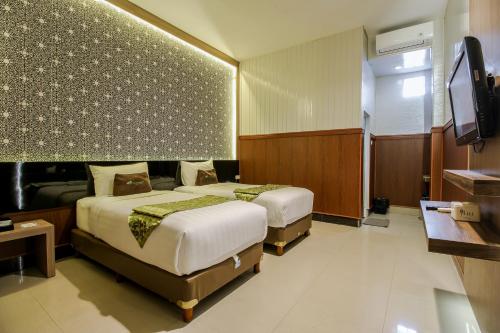 a hotel room with two beds and a flat screen tv at Akasia Budget Hotel in Ulujami