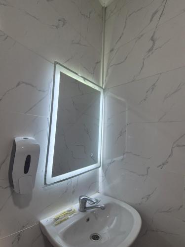 a white bathroom with a mirror and a sink at Green apple in Almaty
