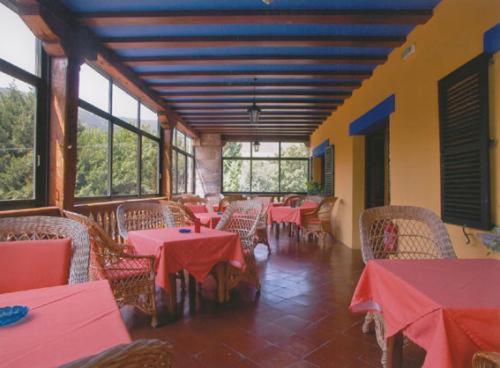 a restaurant with red tables and chairs and windows at Hotel Ibaiondo in Olave