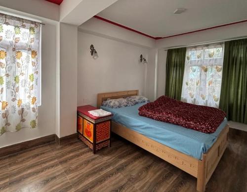 a bedroom with a bed and two windows at Hotel Sonam Chen Residency Lachung in Lachung