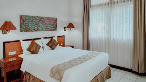 a bedroom with a large white bed and a window at Royal Brongto Hotel in Yogyakarta