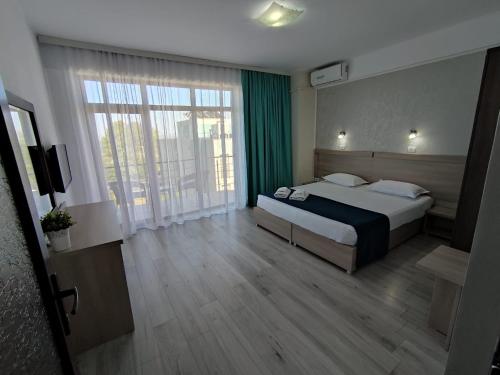 ein Hotelzimmer mit einem Bett und einem großen Fenster in der Unterkunft Vila Elva in Eforie Sud