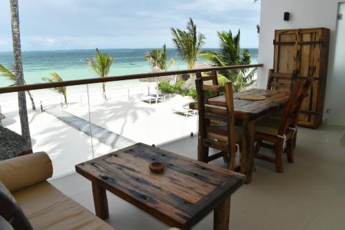 a balcony with a table and chairs and the ocean at Tremendo Beachfront Apartment in Kiwengwa