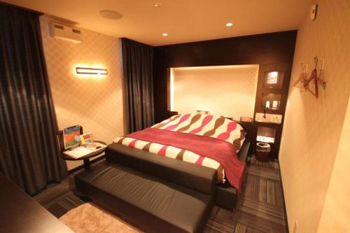 a bedroom with a bed with a red and white blanket at ROOM Ryugasaki in Ushiku
