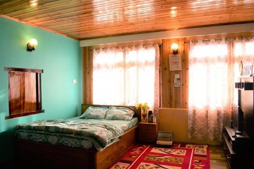 a bedroom with a bed with blue walls and windows at Bungbakha Homestay in Singtām