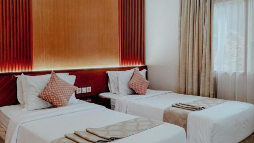 two beds in a hotel room with red accents at Royal Brongto Hotel in Yogyakarta