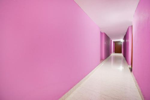 a hallway with purple walls and a white tile floor at Hotel O The Shivansh Inn in Chandanpur