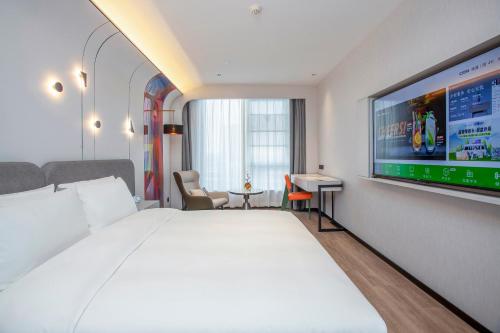 a hotel room with a large bed and a flat screen tv at Ibis Styles Nantong North High-tech Zone in Nantong