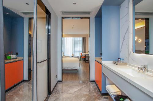 a bathroom with two sinks and a room with a bed at Ibis Styles Nantong North High-tech Zone in Nantong
