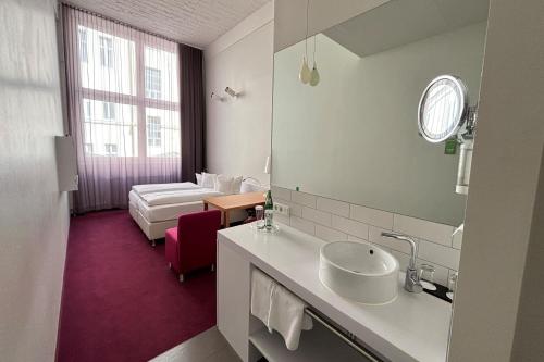a bathroom with a sink and a bed in a room at Wyndham Garden Berlin Mitte in Berlin