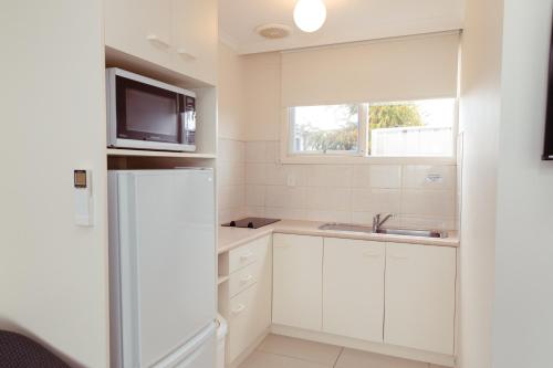a white kitchen with a sink and a refrigerator at Barclay Motor Inn in Devonport