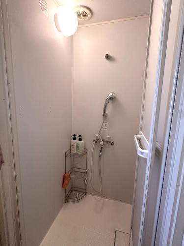 a bathroom with a shower in a white wall at STAY WORK ASAKUSA guest house 浅草店 in Tokyo