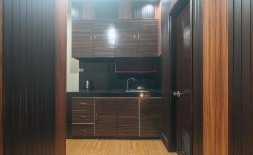 a kitchen with a sink and wooden cabinets at RedDoorz Plus at Canley Residential in Manila