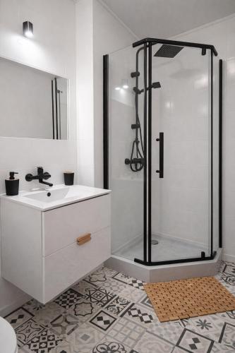 a white bathroom with a shower and a sink at Pokoje nad Dymnem in Koczała