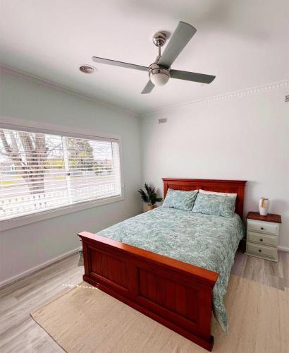 a bedroom with a bed and a ceiling fan at Sam's Cottage on Hennessey in Moe