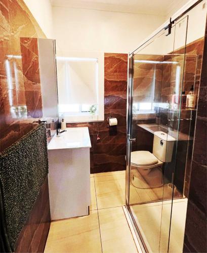 a bathroom with a shower and a sink and a toilet at Sam's Cottage on Hennessey in Moe