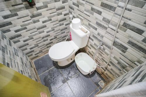 a bathroom with a white toilet in a brick wall at Joglo Prambanan B3 in Bugisan