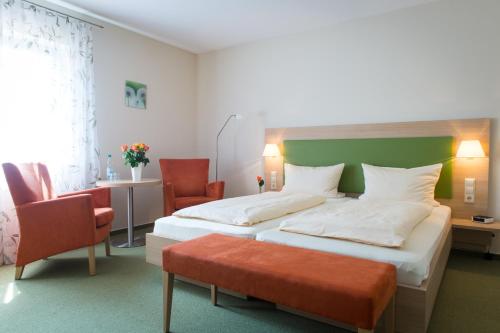 a hotel room with two beds and a chair at Gästehaus Höferlin in Bad Bellingen