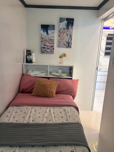 a small bedroom with a bed with red sheets at DG Luxe Suites - Cabanatuan in Bangad