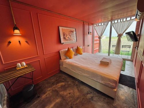 a bedroom with a bed with red walls and a window at Padi Box Homestay in Sekinchan