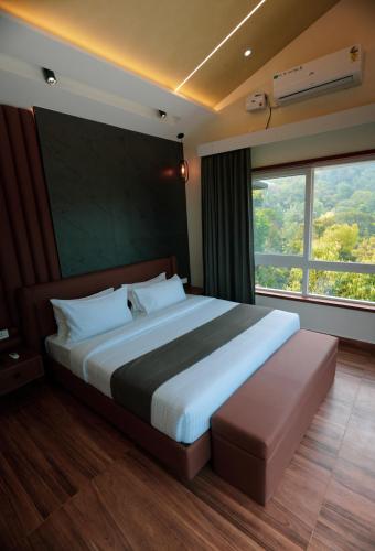 a bedroom with a large bed and a large window at Ymoon Mountain Resort Wayanad in Koroth