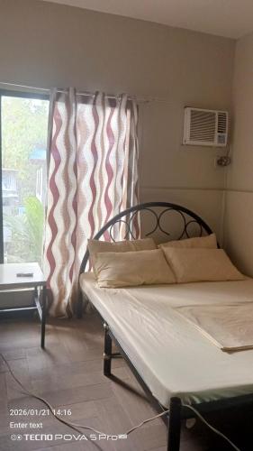 a bedroom with a bed and a window with curtains at Little John's Town Inn in Coron