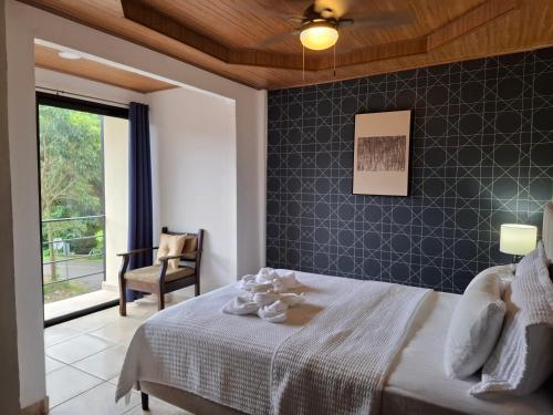 a bedroom with a bed and a chair and a window at Hotel La Casa de la Abuela in Boquete