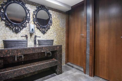 a bathroom with two sinks and two mirrors at Achilleos City Hotel in Larnaca