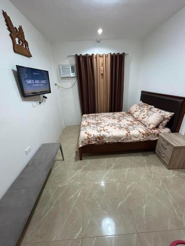 a bedroom with a bed and a tv in it at Yalyn's Hometel Kabankalan in Kabankalan
