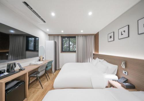 a hotel room with two beds and a desk at Lantana Daegu Shinam Branch in Daegu