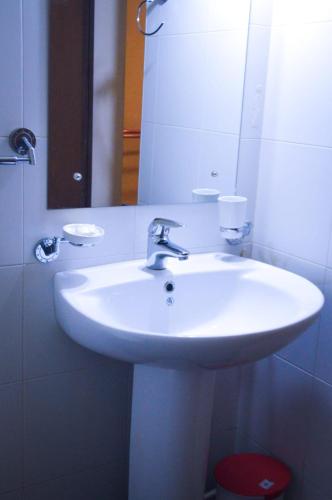 a bathroom with a white sink and a mirror at Gilbys Eco Bungalow in Udaweliwitiya