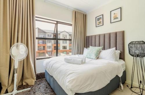 a bedroom with a large bed and a large window at AlimamaSpaces The Lavender in Northriding